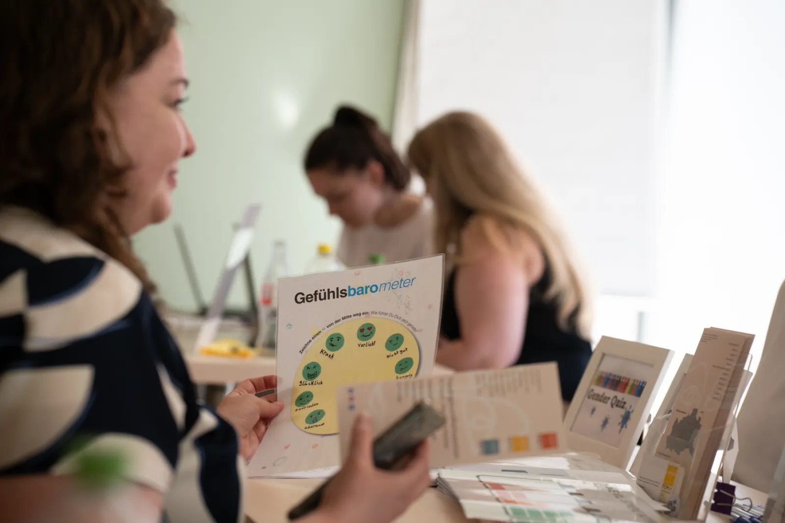 Person liest Broschüre Gefühlsbarometer am Infostand mit weiteren Unterlagen