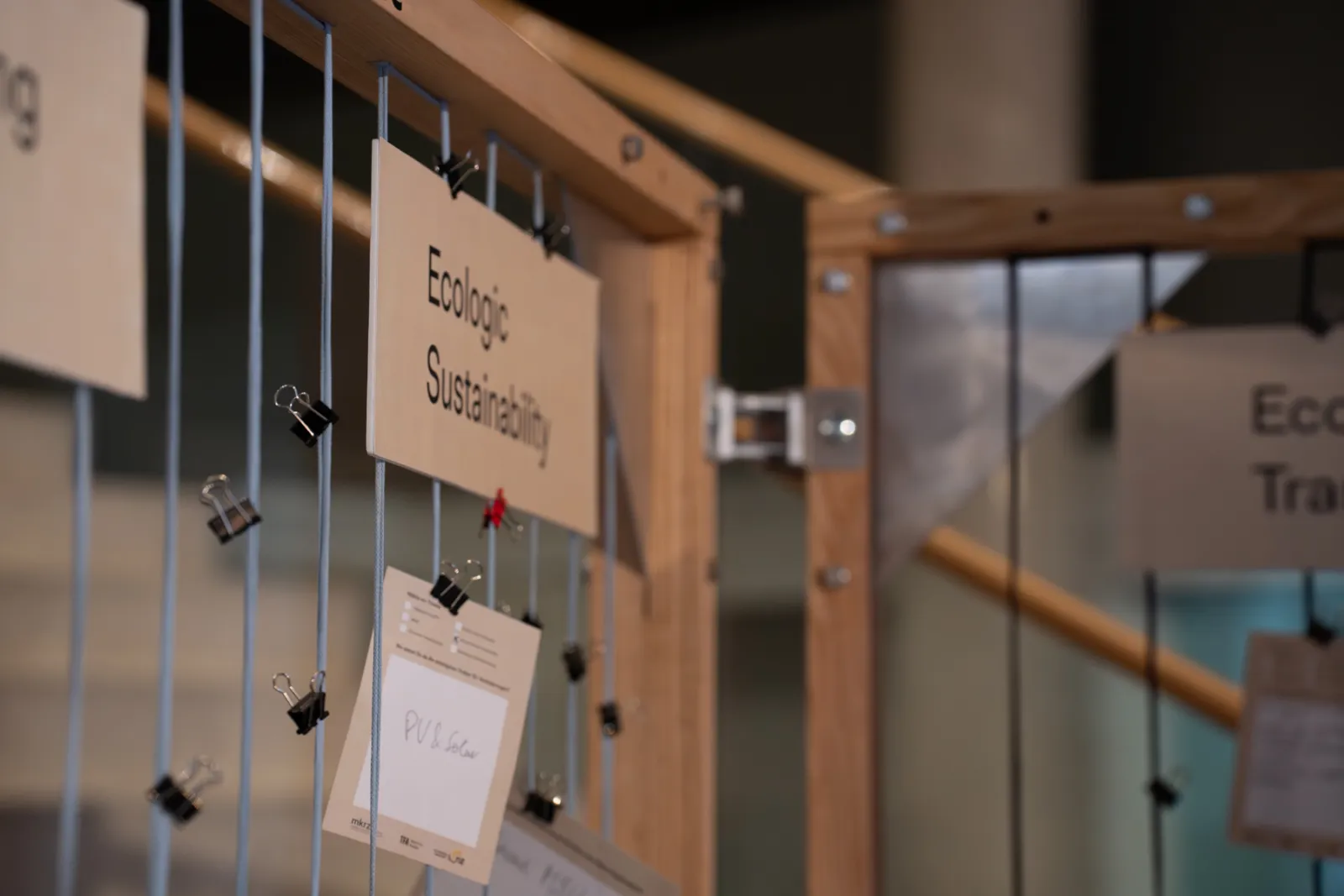 Holzrahmen-Display mit hängenden Karten, befestigt durch Clips; Ausstellung zum Thema Ökologie und Nachhaltigkeit.