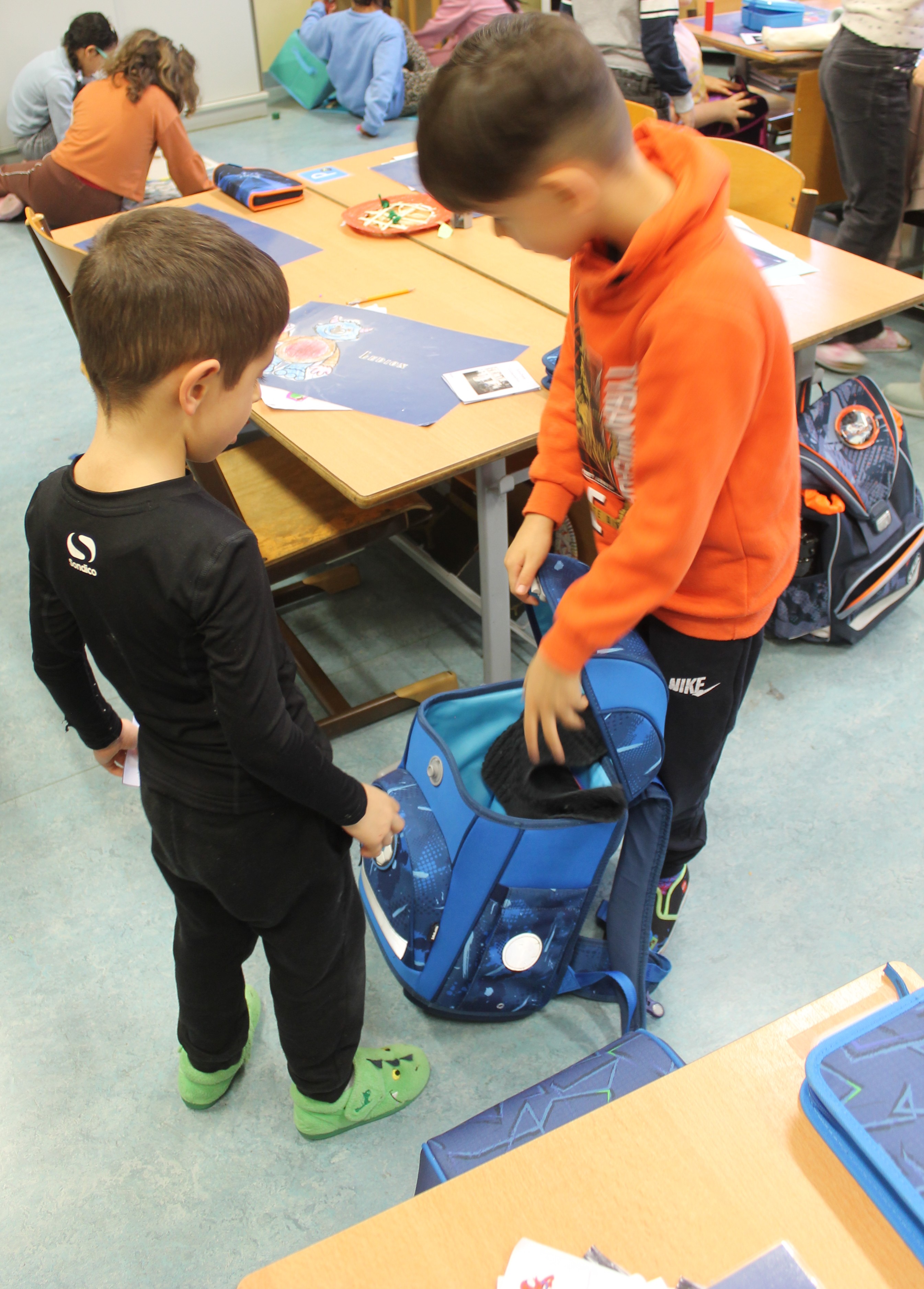 Schulkind zeigt Kindergartenkind seine Schultasche beim 2. Schulbesuch