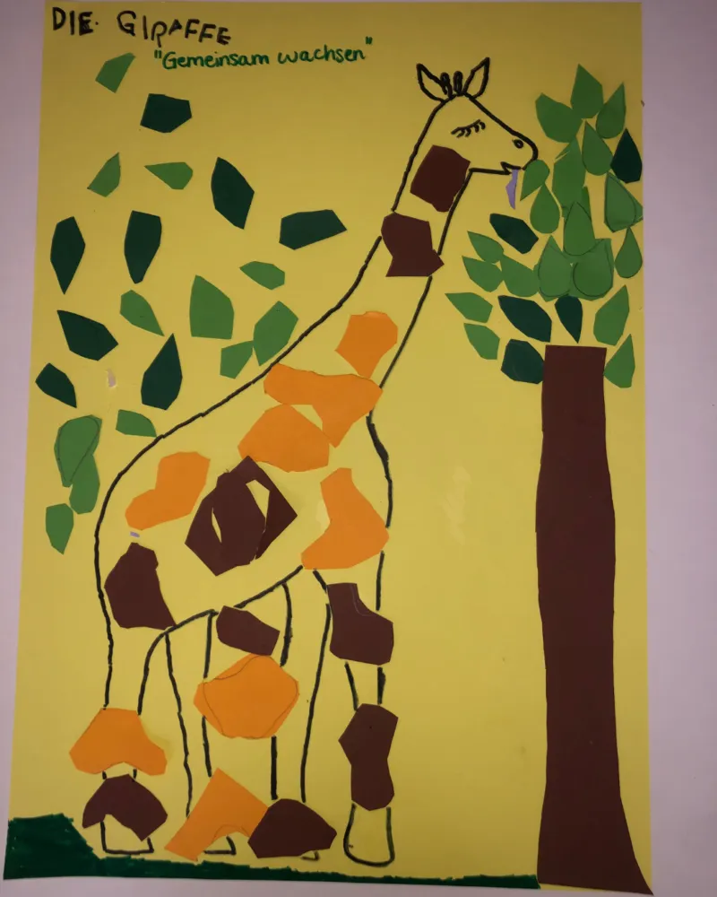 Giraffe aus bunten Papierformen vor gelbem Hintergrund; Baum rechts, grüne Blätter links; Titel: Die Giraffe - Gemeinsam wachsen.